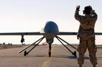 A senior airman marshals an RQ-1 Predator drone at Tallil Air Base, Iraq, in January 2008. (US Air Force photo/Suzanne Jenkins)