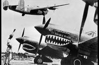 A U.S. Army Air Forces Liberator bomber crosses the shark-nosed bows of U.S. P-40 fighter planes at a U.S. base in China ca. 1943. (National Archives photo)