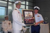 Cutter Diligence former commanding officer Capt. Jeffrey Randall receives a parting gift of a framed painting with a commissioning pennant and three unique coins. (U.S. Coast Guard photo)