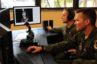 Tech. Sgt. Benjamin Hoffman and Maj. Michael Fleming monitor Col. James Fisher on the video feed from the cockpit of the new spatial disorientation simulator Aug. 5, 2015, at Columbus Air Force Base, Miss. (U.S. Air Force photo/Airman 1st Class John Day)