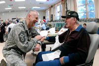 An Air Force senior master sergeant greets a Marine Corps veteran at the North Dakota Veteran's Nursing Home in Lisbon, N.D. Under the new VA budget plan, pensions would be reduced for some veterans in nursing homes. (US Air Force photo/David Lipp)