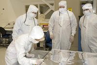 Lab workers in white coveralls.