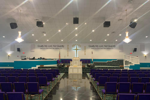 The altar of the main church for the House of Prayer in Hinesville, Georgia, features a large cross and a reference to a verse from the gospel of Matthew.