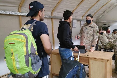 U.S. Army soldiers help Afghan evacuee interpreters through the registration process on a U.S. military base in Kuwait.