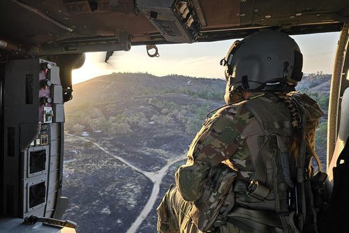 U.S. Army Reserve Spc. Shavaun Brugger, a UH-60 helicopter repairer assigned to Charlie Company, 7th Battalion, 158th Aviation Regiment, peers out of the door of a Black Hawk during Mojave Falcon 2025 at Fort Hunter Liggett, California.