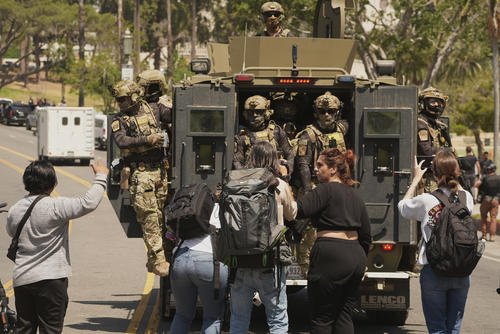 Federal agents ride on an armored vehicle in Los Angeles.