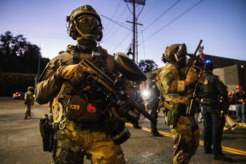 Federal enforcement officers stand guard near a U.S. Immigration and Customs Enforcement facility in Portland, Ore.