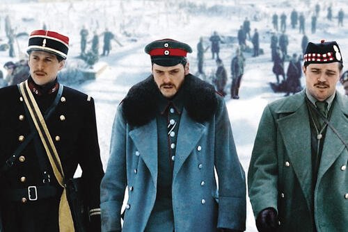 Three World War I officers in winter uniforms walk through a snowy landscape while groups of soldiers gather in the background.