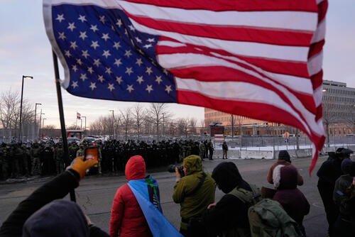 A person holds an upside-down American flag.