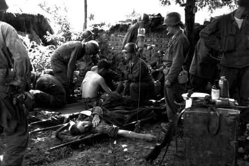 Wounded American soldiers are given medical treatment at a first aid station, somewhere in Korea. July 25, 1950. Pfc. Tom Nebbia. (Army)